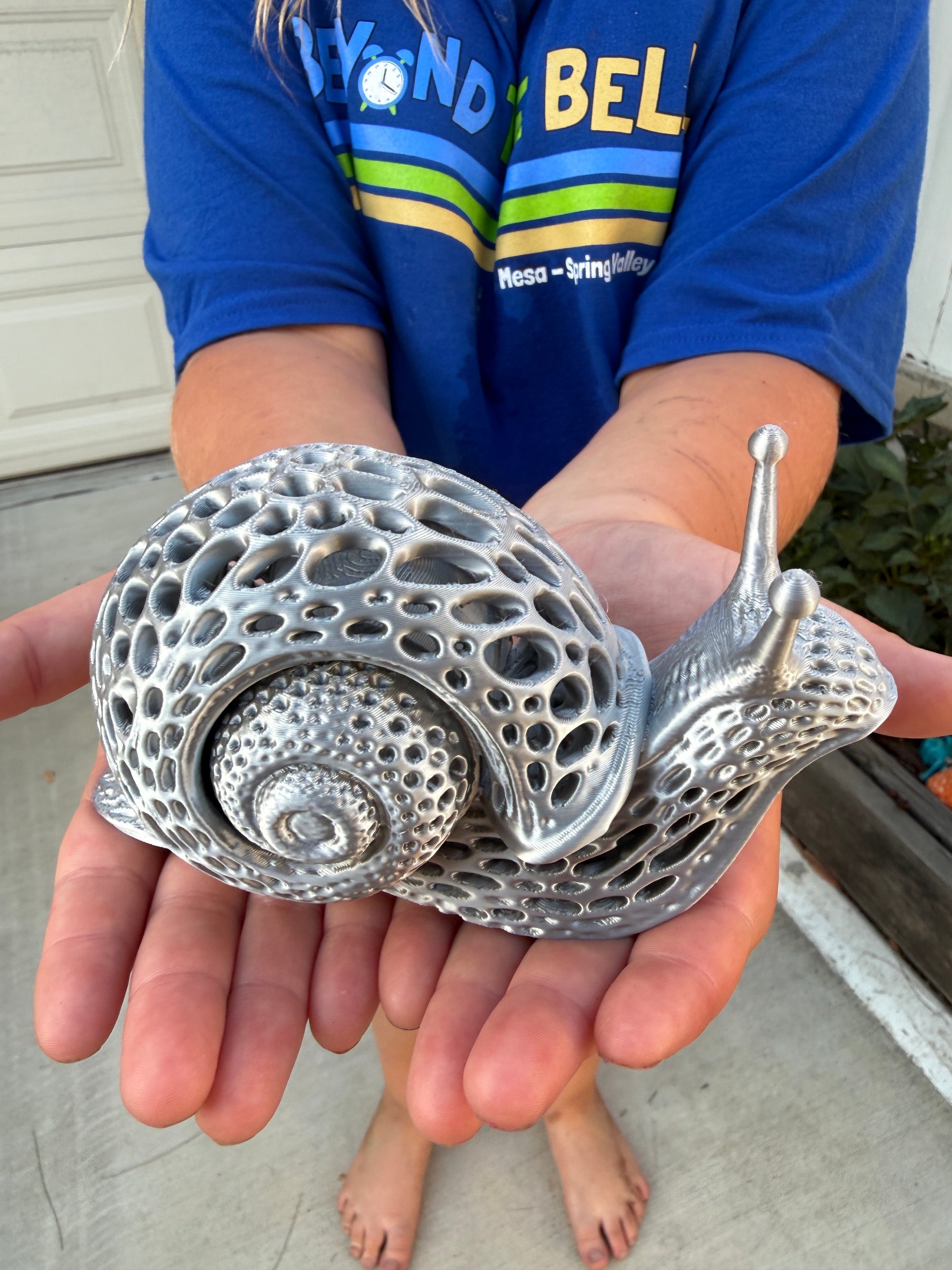 Silver 3D printed snail held in Nora's hands